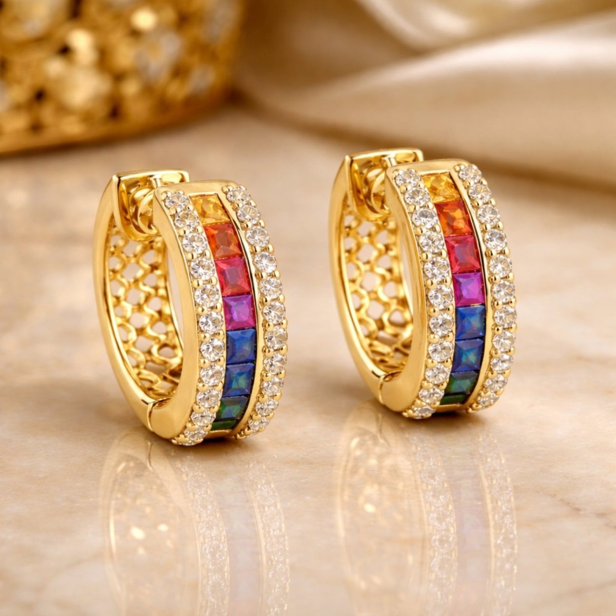 Detailed view of the Kouvr Yasmina rainbow hoop earrings on a marble surface, highlighting the honeycomb interior gallery and the vibrant colors of the channel-set sapphires.