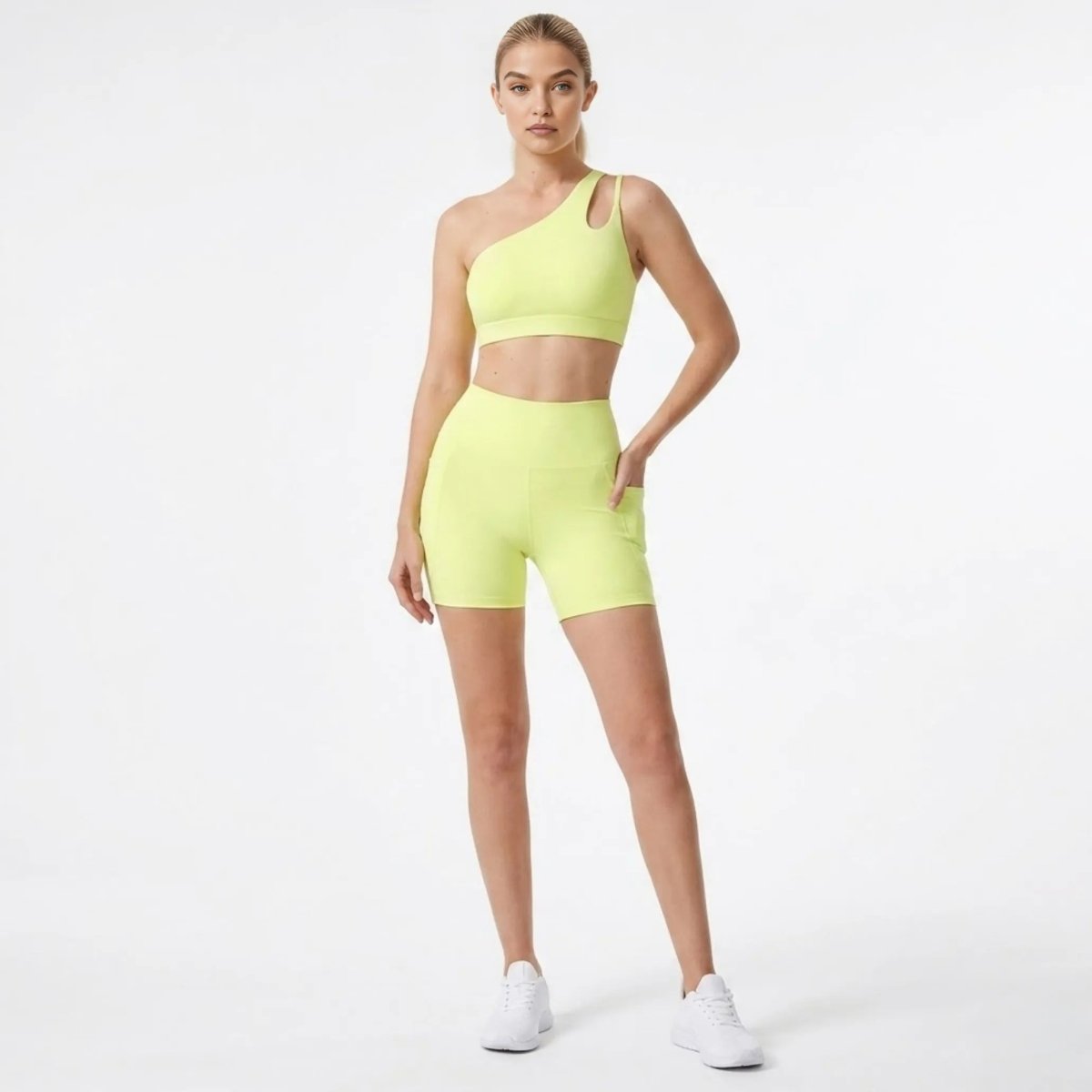 Woman wearing Kouvr yellow asymmetric one shoulder sports bra and high waisted biker shorts set with pockets front full body view