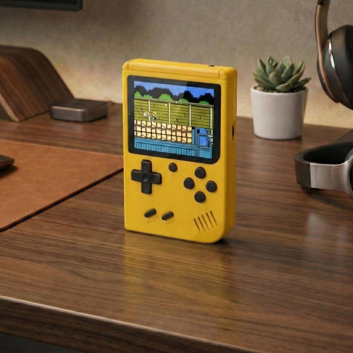 Yellow Kouvr retro handheld game console with a 3-inch color screen showing a classic 8-bit game.