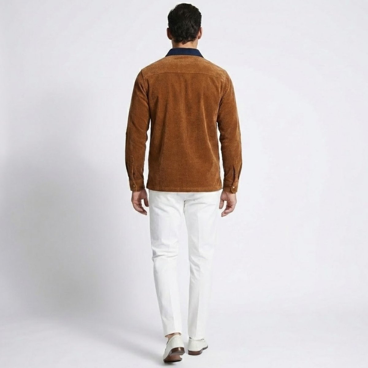 Back view of the Kouvr Zain orange corduroy polo shirt, detailing the back yoke and navy collar contrast.