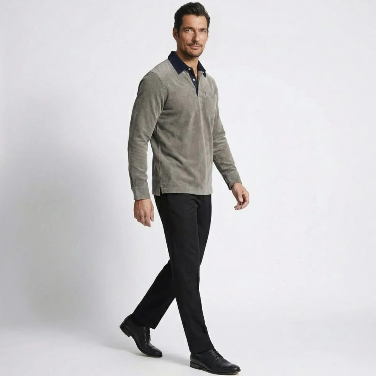 Side profile of a model walking in the Kouvr Zain grey corduroy long sleeve polo, showing the shirt's fit and texture.