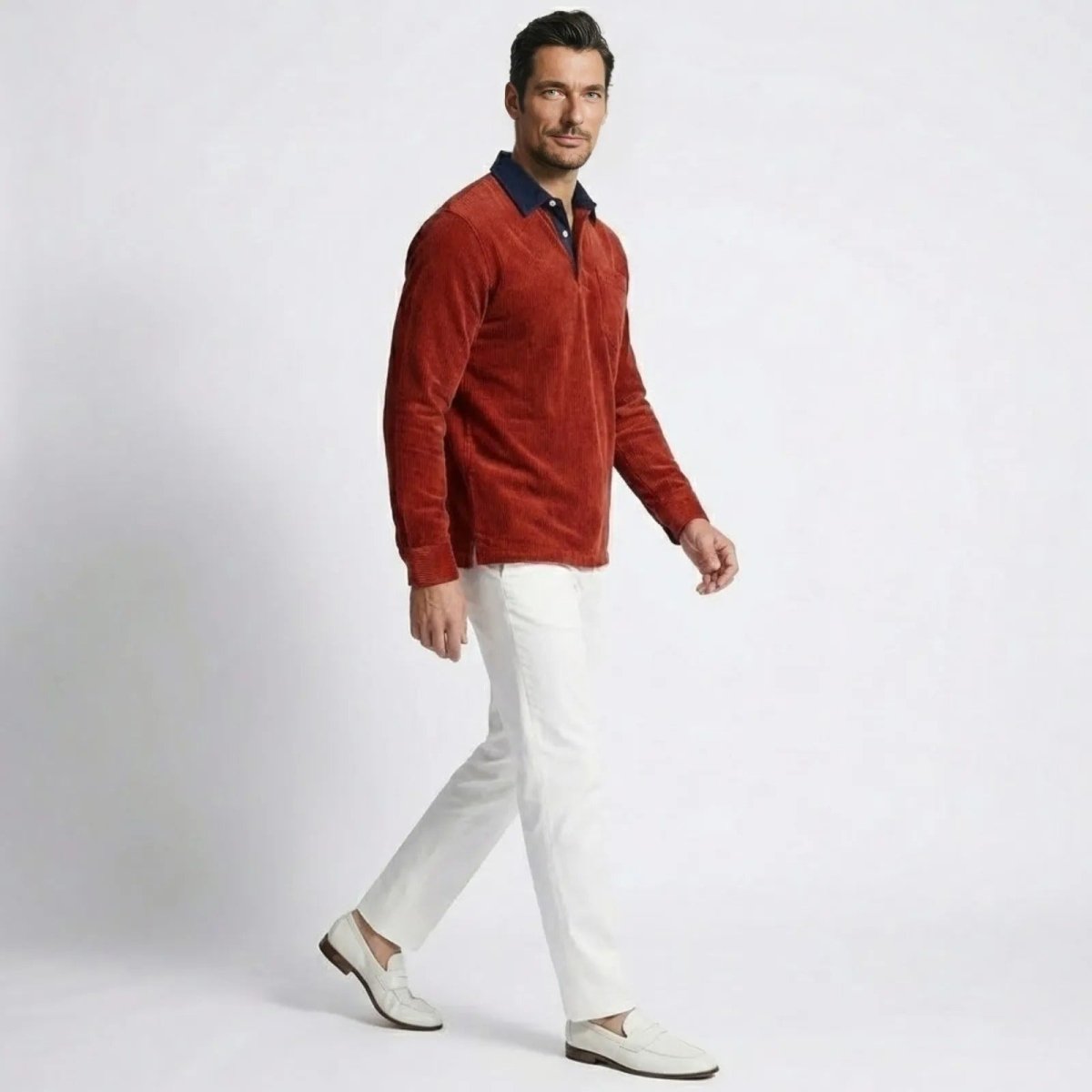 Side profile of a model walking in the Kouvr Zian red corduroy long sleeve polo, showing the shirt's fit and drape.