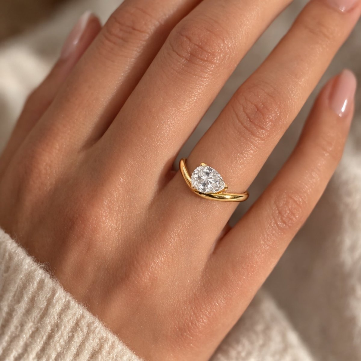 Close-up lifestyle shot of the Kouvr Zoella modern heart shaped solitaire ring on a model's hand.