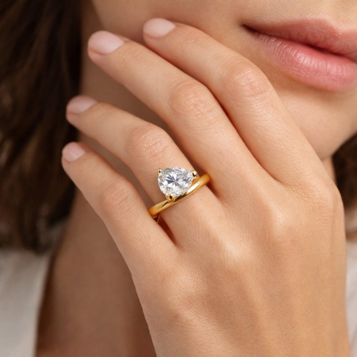 Close up view of the Kouvr Zuri 2 carat pear cut diamond engagement ring on a woman's finger, showcasing the unique swirl band design.
