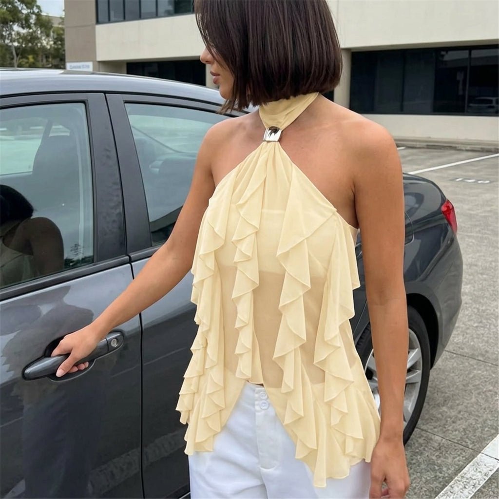 Woman stepping out of a car wearing the Kouvr pale yellow cascading ruffle halter blouse with white pants for an elegant daytime look.