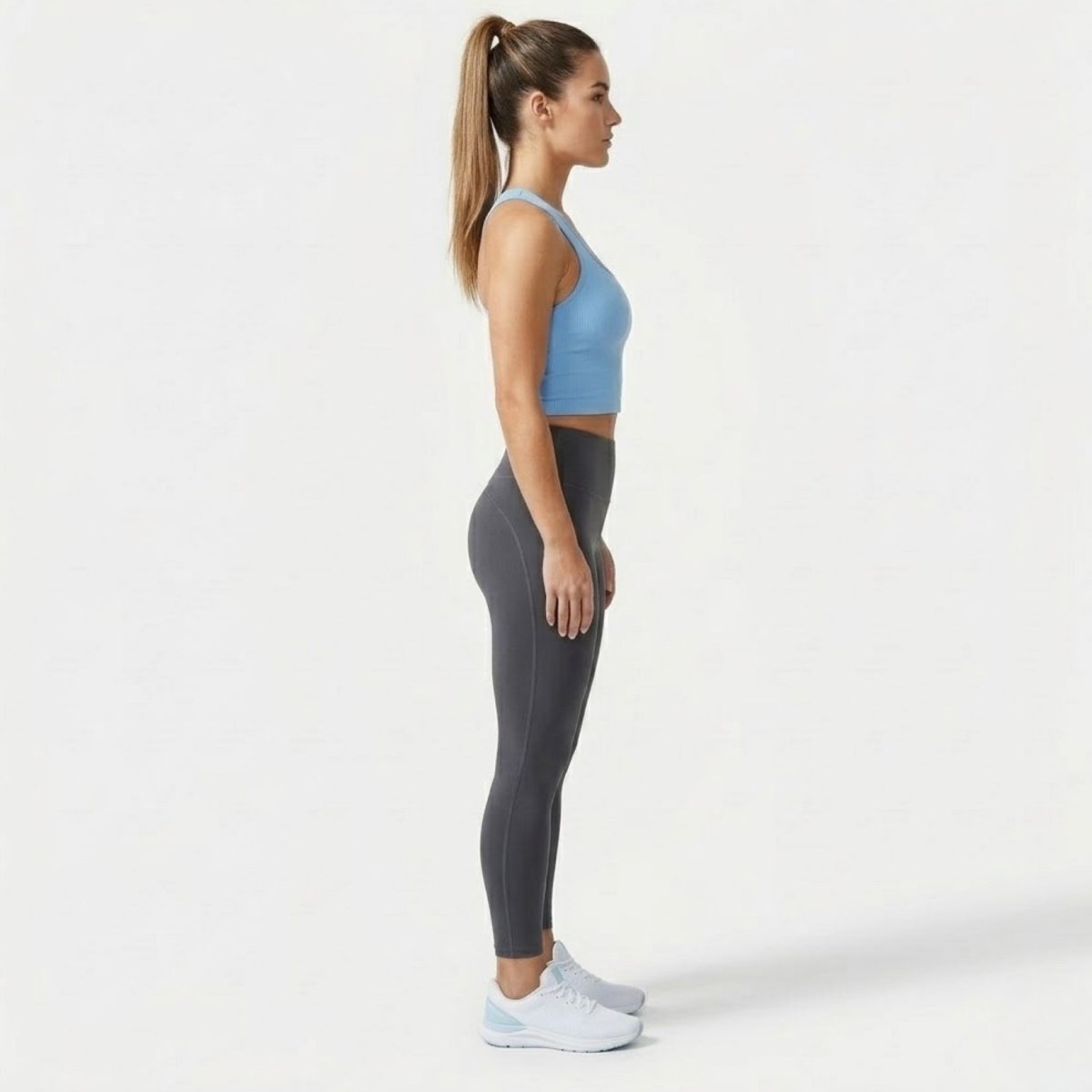 Side profile of woman in fitted light blue workout crop top and athletic leggings
