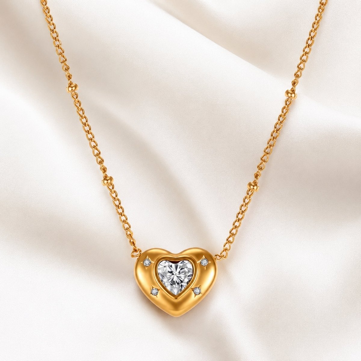 Elegant gold heart necklace by Kouvr gracefully laid out on white silk fabric highlighting its polished finish.