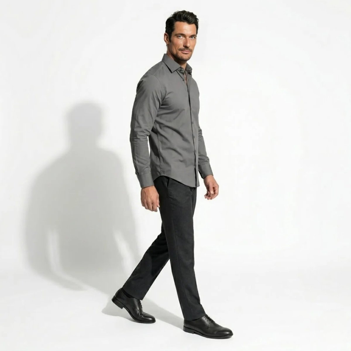 Side profile of male model walking in tailored grey long sleeve button up dress shirt by Kouvr