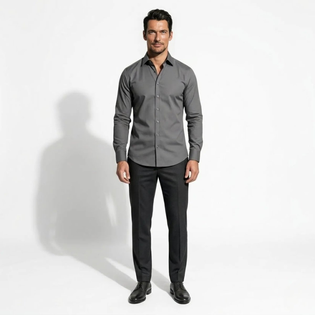 Man wearing Kouvr charcoal grey slim fit long sleeve dress shirt and dark trousers facing forward against a white background