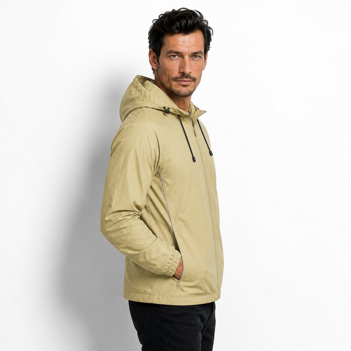 Side profile of male model wearing the Kouvr light army green technical athletic outerwear showing reflective piping detail.