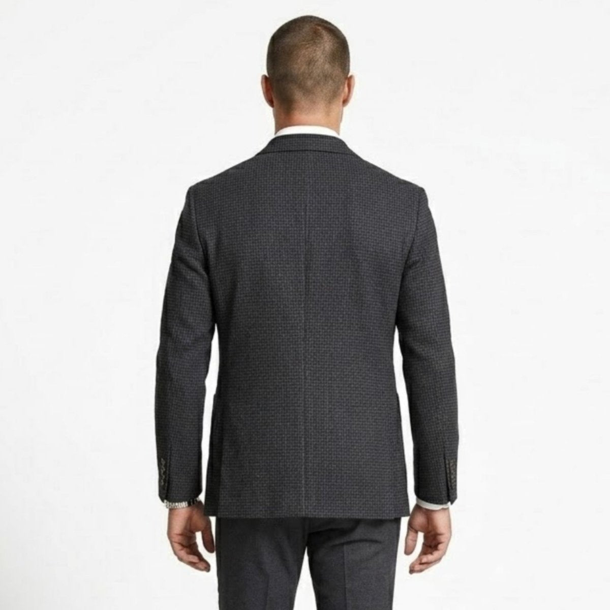 Close up back view of a man wearing a plaid slim fit sport coat showing double vent details.