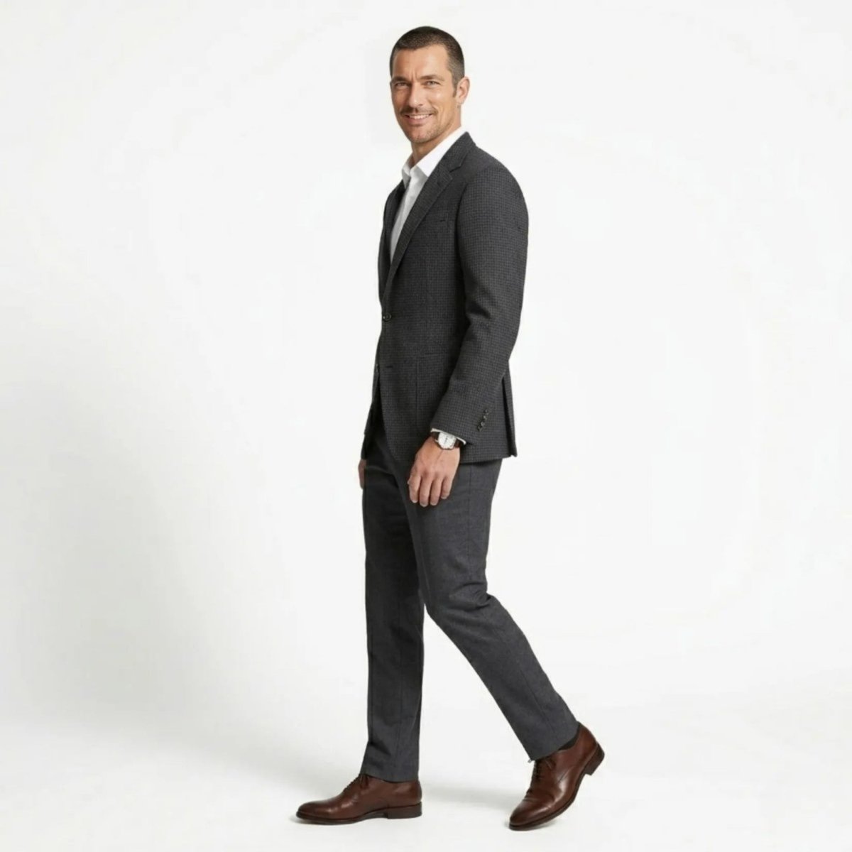 Side profile of a man walking confidently in a plaid two button patch pocket blazer.