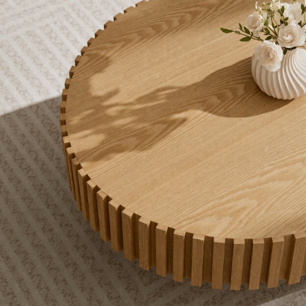 Fluted oval wood coffee table with solid pedestal base in a sunlit organic modern living room.