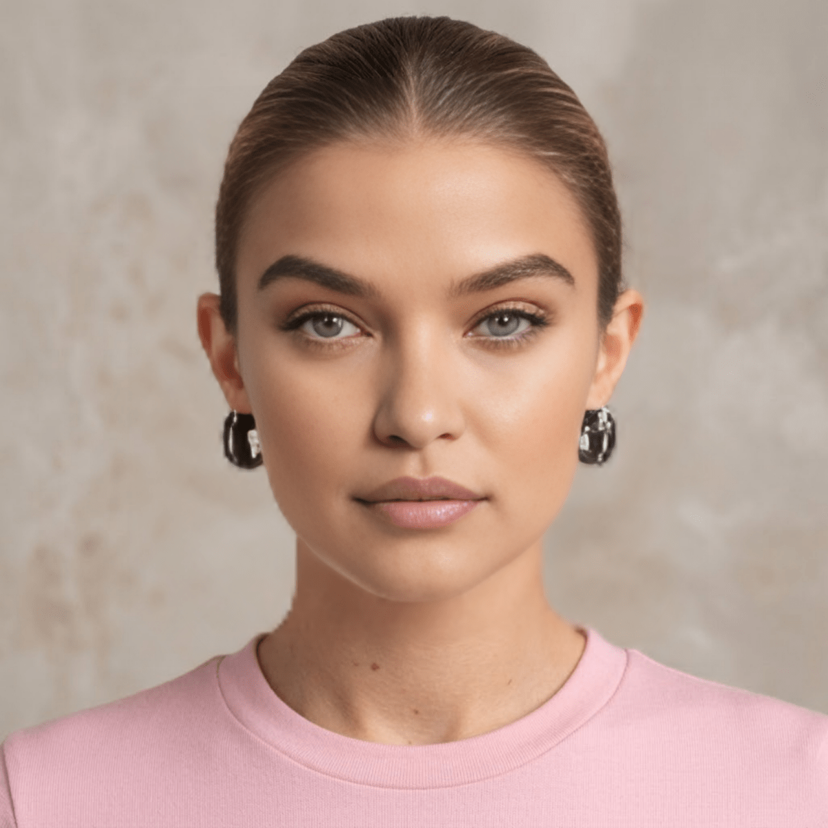 A model with her hair pulled back showcasing the Kouvr black and white diamond barrel huggie earrings for scale and styling.