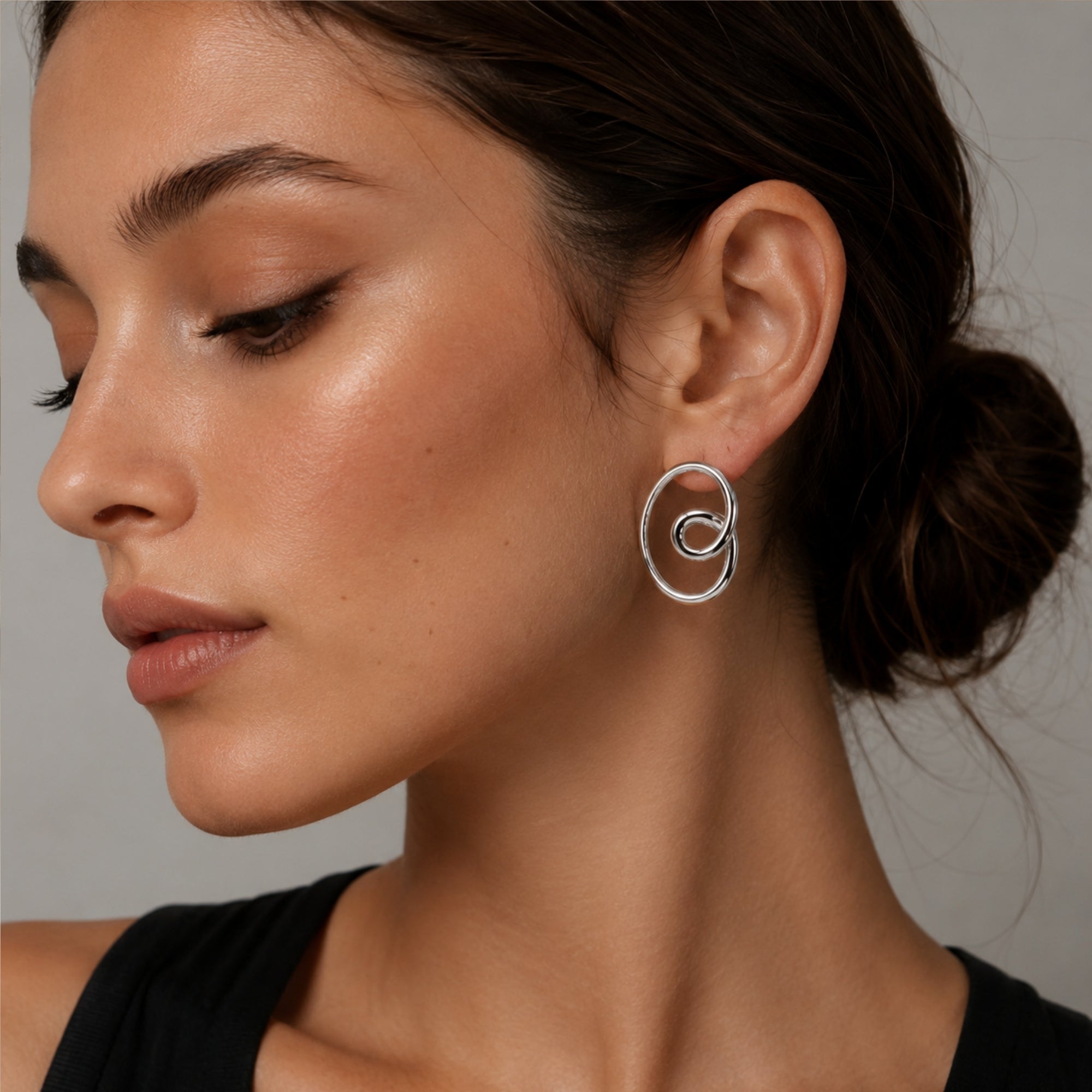 Elegant woman wearing Kouvr silver geometric abstract circle statement stud earrings, showcasing the perfect 36mm drop size and polished finish.
