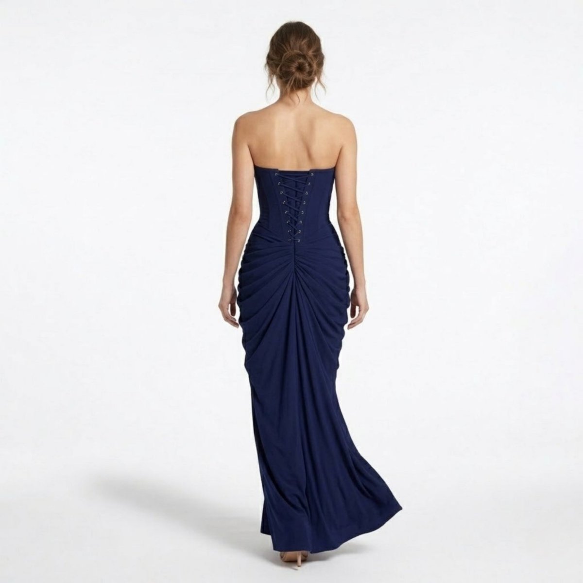 Back view of a navy blue formal maxi dress highlighting the adjustable lace-up corset back and elegant skirt drape.