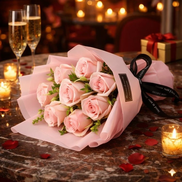 A hand-tied bouquet of 9 light pink forever roses from Kouvr, wrapped in pink paper, held by a woman in a romantic Parisian setting.