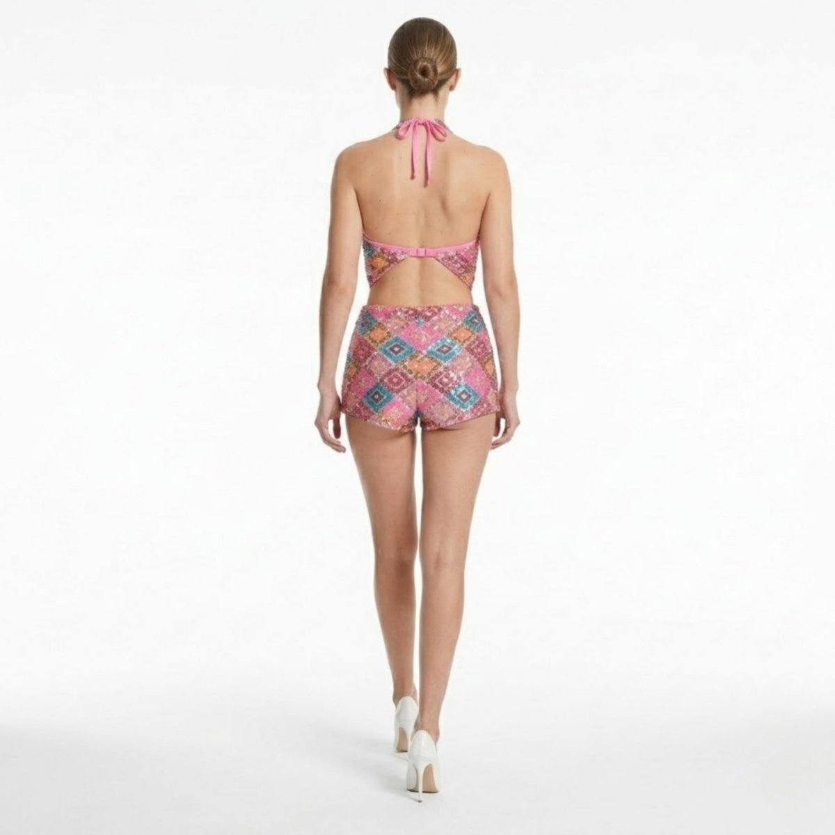 Back view of open back pink sequin mini romper showing adjustable bra-style clasp and halter neck tie fastening.