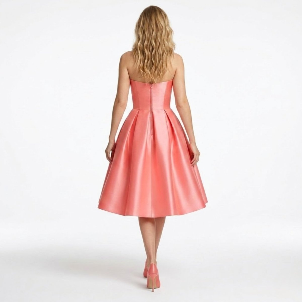 Back view of the strapless coral pink formal midi dress showing the hidden zipper and wide pleated skirt drape.