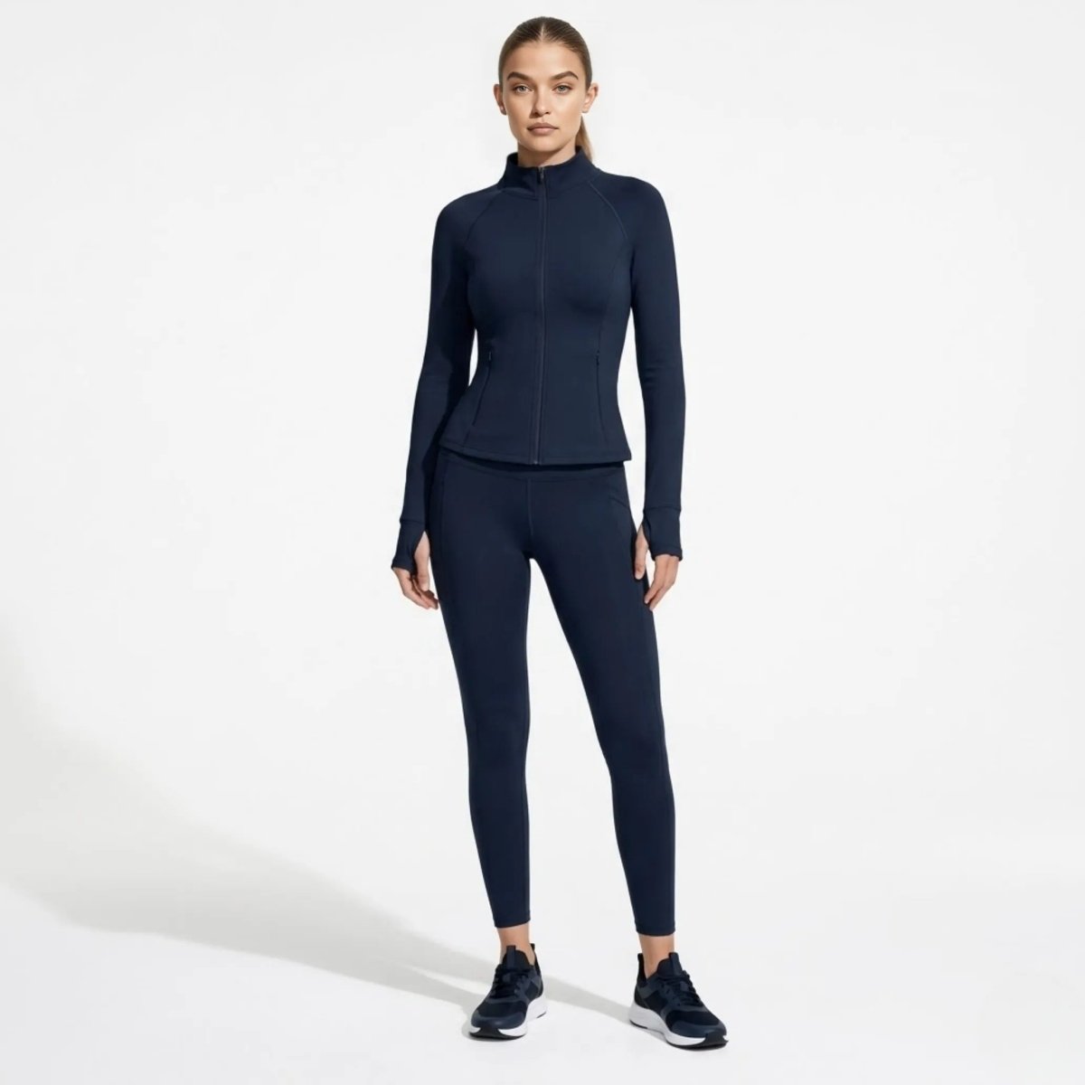 Full body shot of woman in navy blue activewear zip-up jacket and matching leggings