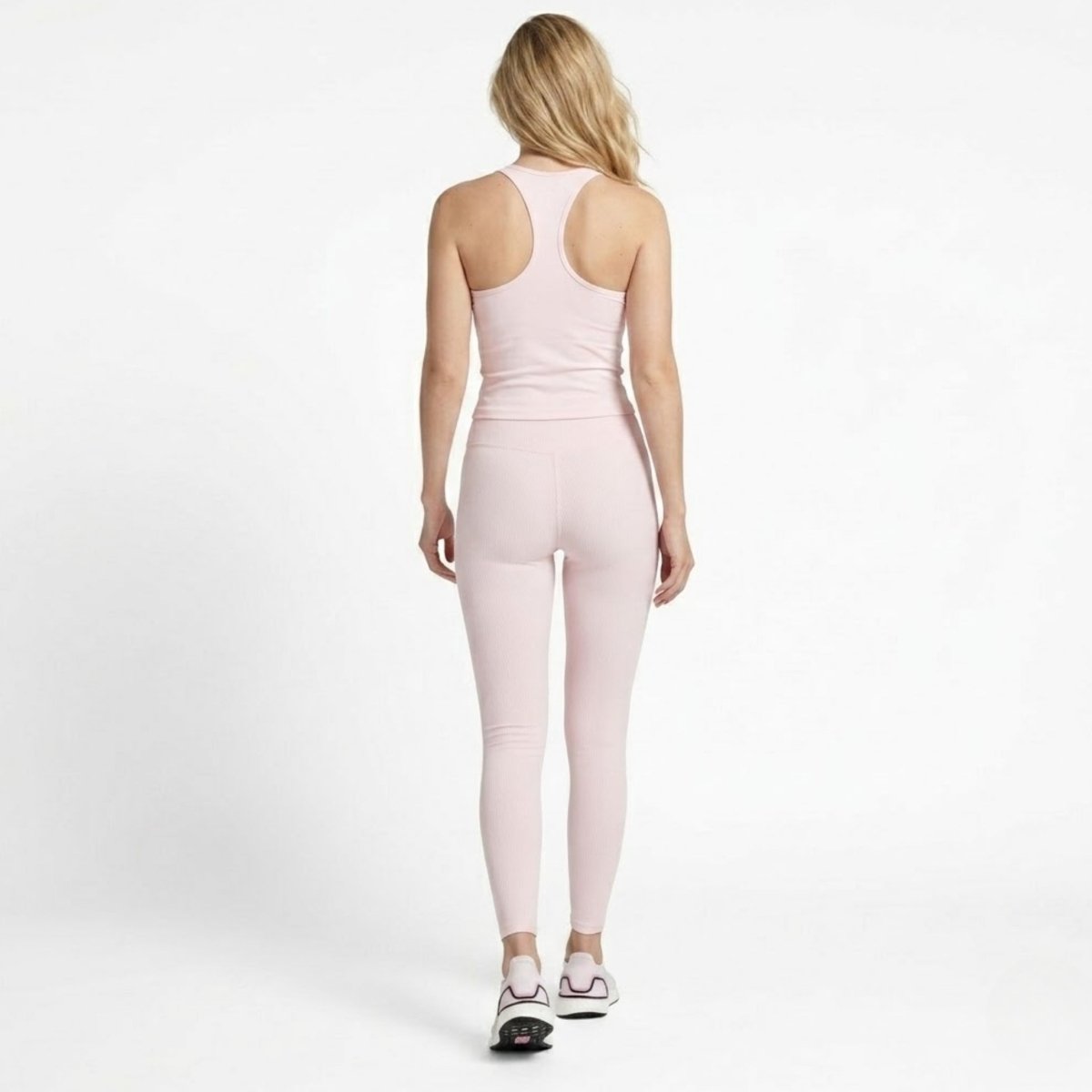 Full body back view showing the sculpting fit of the pink ribbed leggings and supportive racerback top.