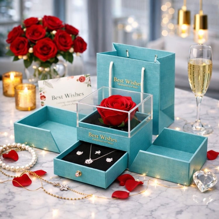Open teal jewelry gift box featuring a preserved red rose in a clear acrylic case and a slide-out drawer containing a silver flower pendant necklace and earrings.