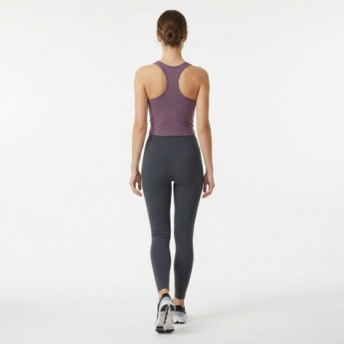 Full back view of woman walking in Kouvr purple seamless racerback yoga top.