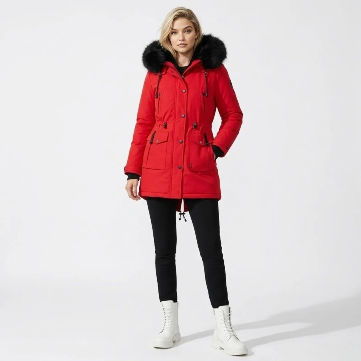 Woman wearing Kouvr red winter parka coat with black faux fur hood standing facing forward