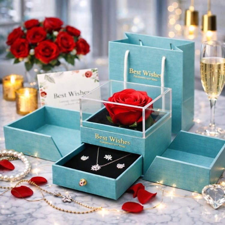Romantic Valentine's Day gift set for her including an eternal red rose display box, silver jewelry set, and matching 'Best Wishes' gift bag surrounded by candles and champagne