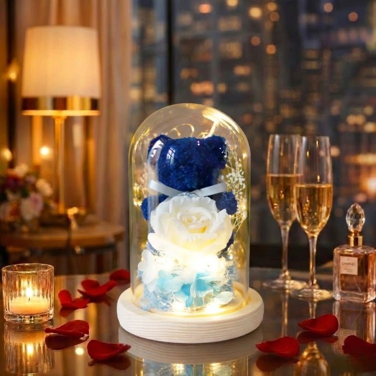 Unique navy blue preserved flower bear holding a white rose in a glass dome with LED illumination.