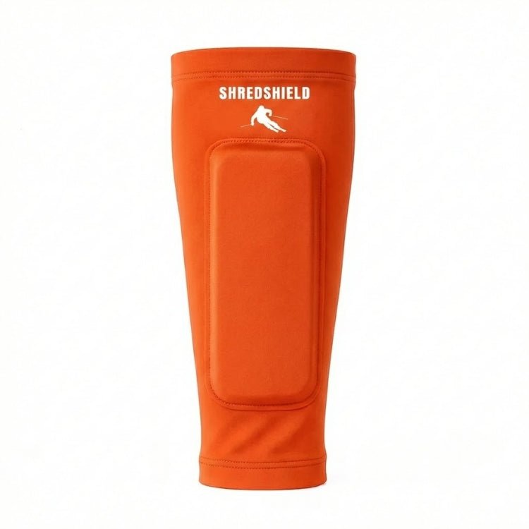 Front view of the orange ShredShield ski shin guard with a matching orange gel protective pad and white logo, against a plain white background.