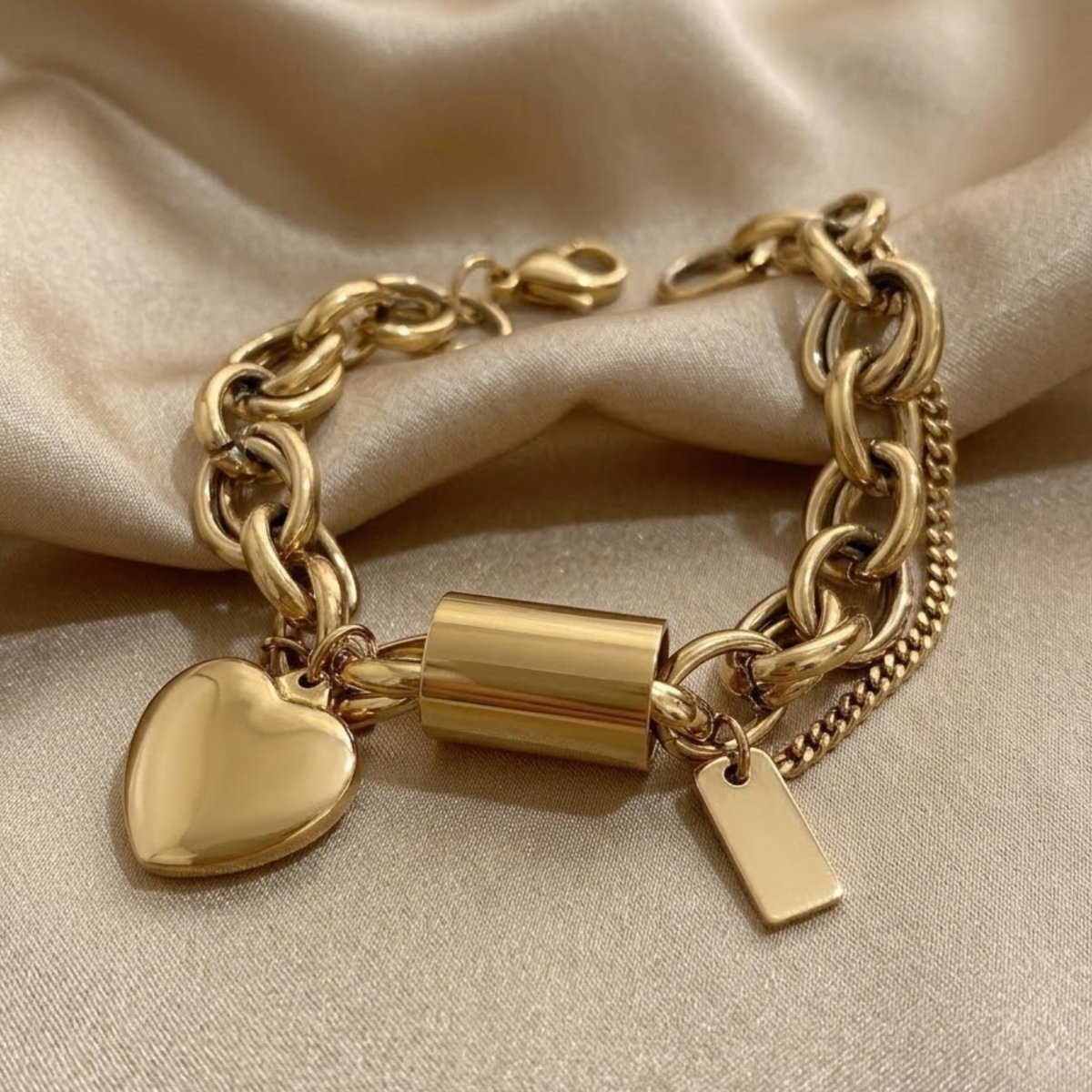 Polished silver-tone chunky link bracelet with heart charms and a barrel clasp in a luxury gift box display.