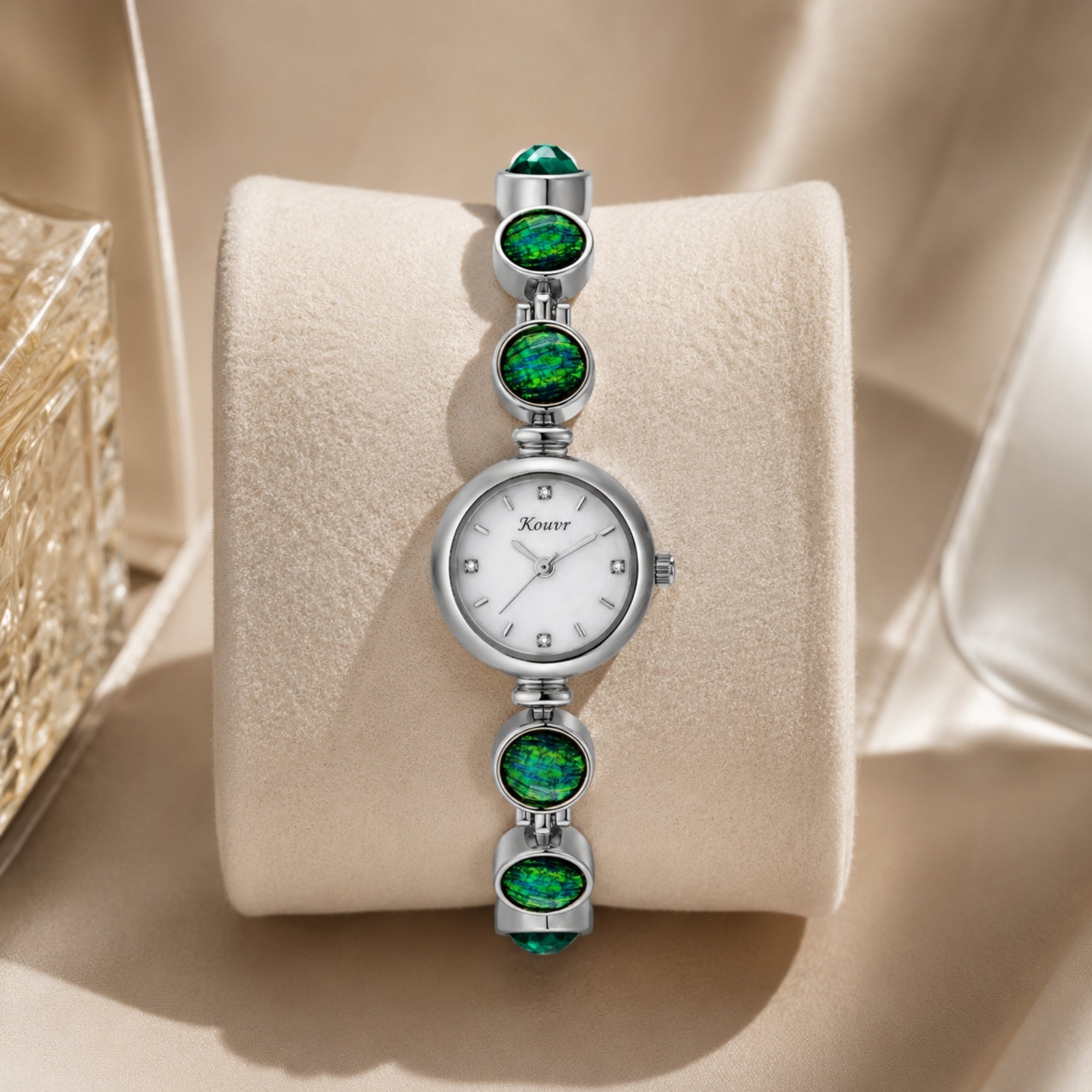 Upright display shot of the Kouvr silver women's watch beautifully showcasing the mesmerizing green bracelet stones and shimmering mother of pearl dial.