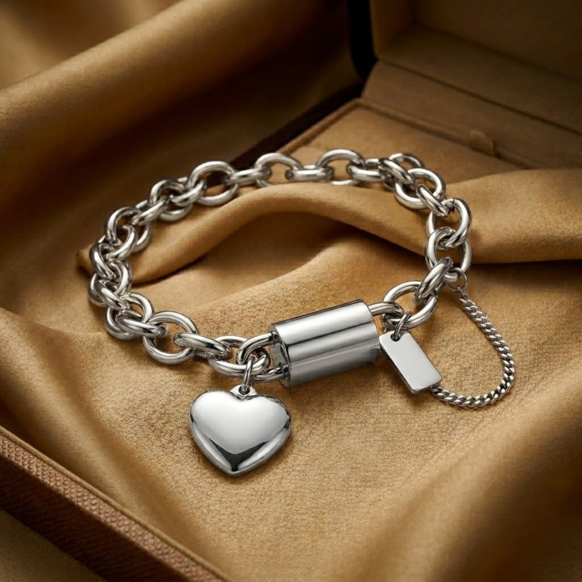 Aesthetic product shot of a tarnish-resistant stainless steel chunky bracelet with a dangling heart charm on satin.