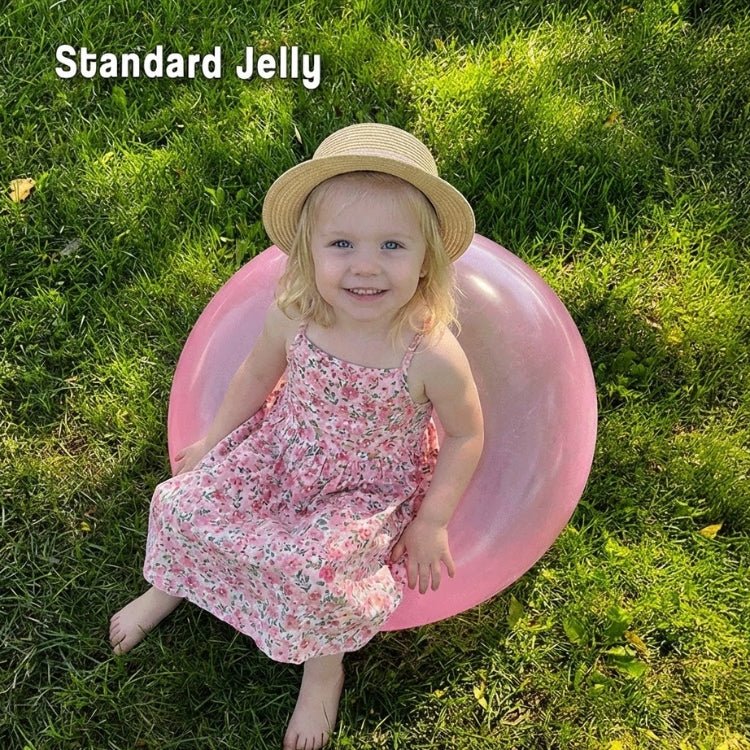 A cute toddler girl in a hat sitting comfortably on a pink standard-sized jelly balloon ball, perfect for sensory play and gentle bouncing.