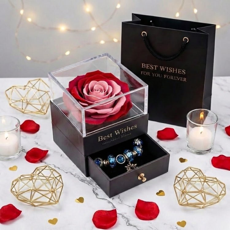 Top-down view of a romantic red and pink two-tone eternal rose inside a square gift box, surrounded by candles.