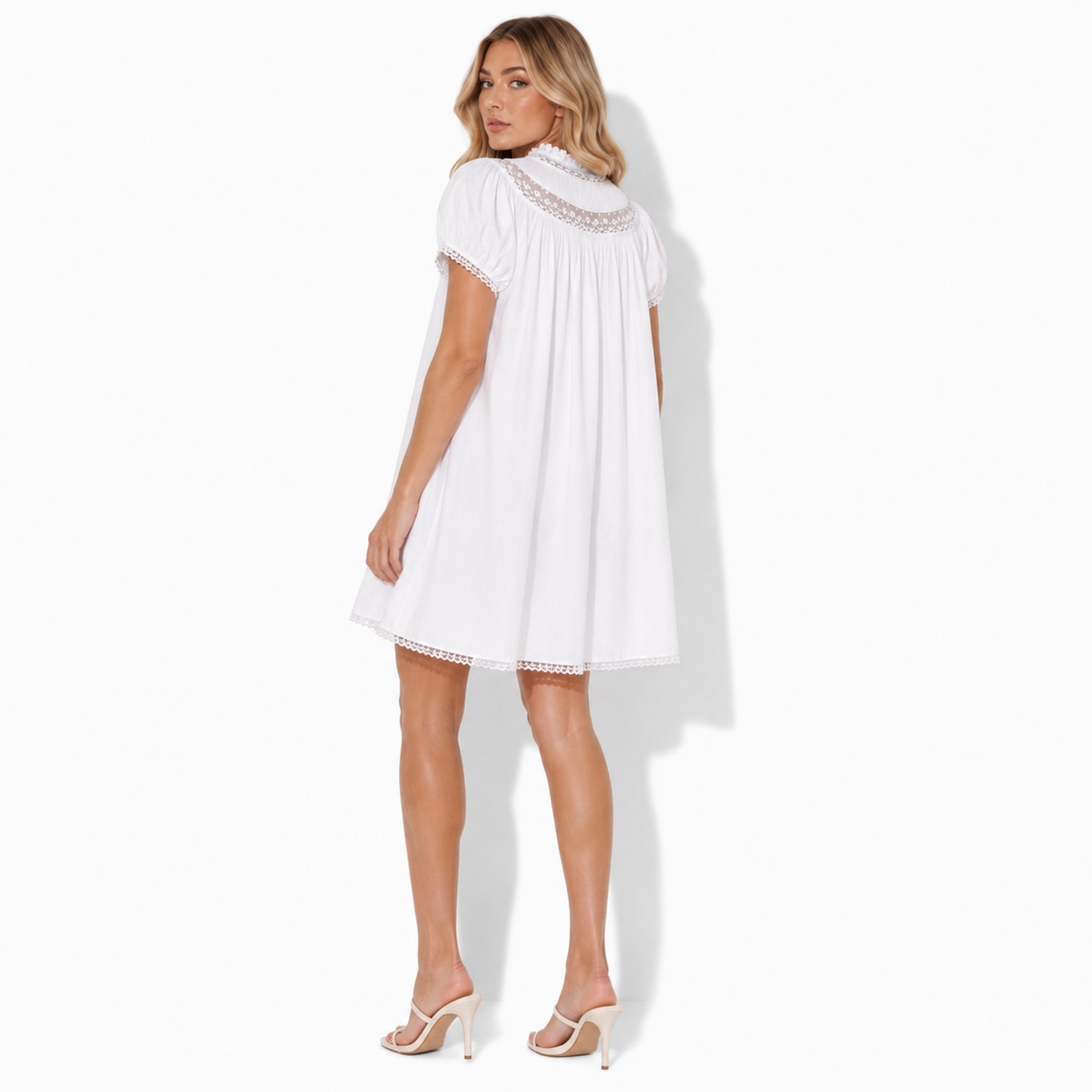 Back view of white cotton mini dress showing gathered pleats and sheer lace shoulder yoke.