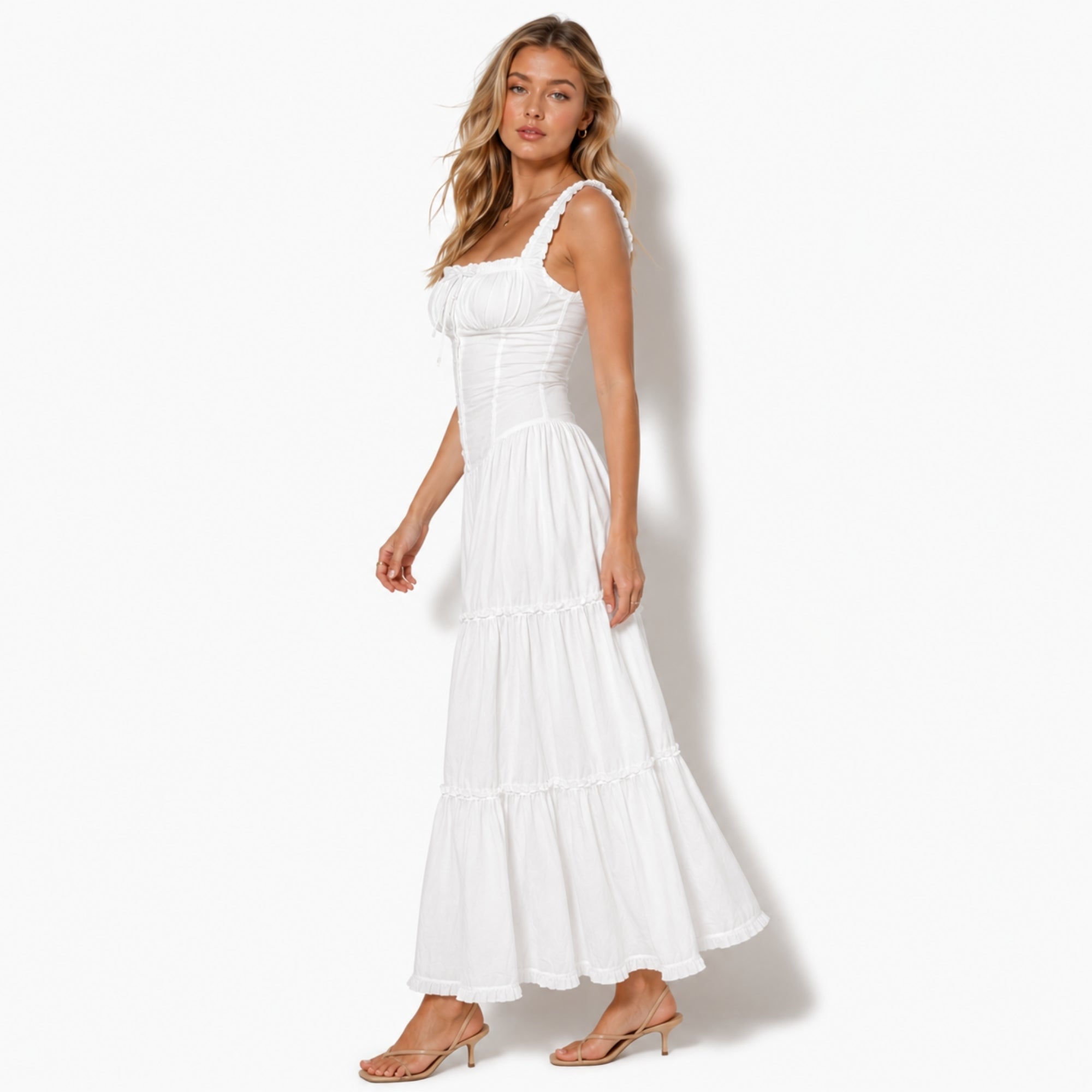 Side profile of a fashion model walking in a white cottagecore maxi dress showcasing the romantic draped layers and flattering fit.