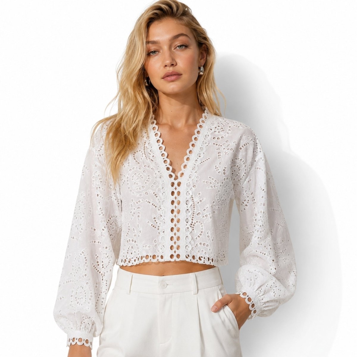 Front view of the Kouvr white eyelet lace V-neck crop top with long balloon sleeves styled with high-waisted white trousers.