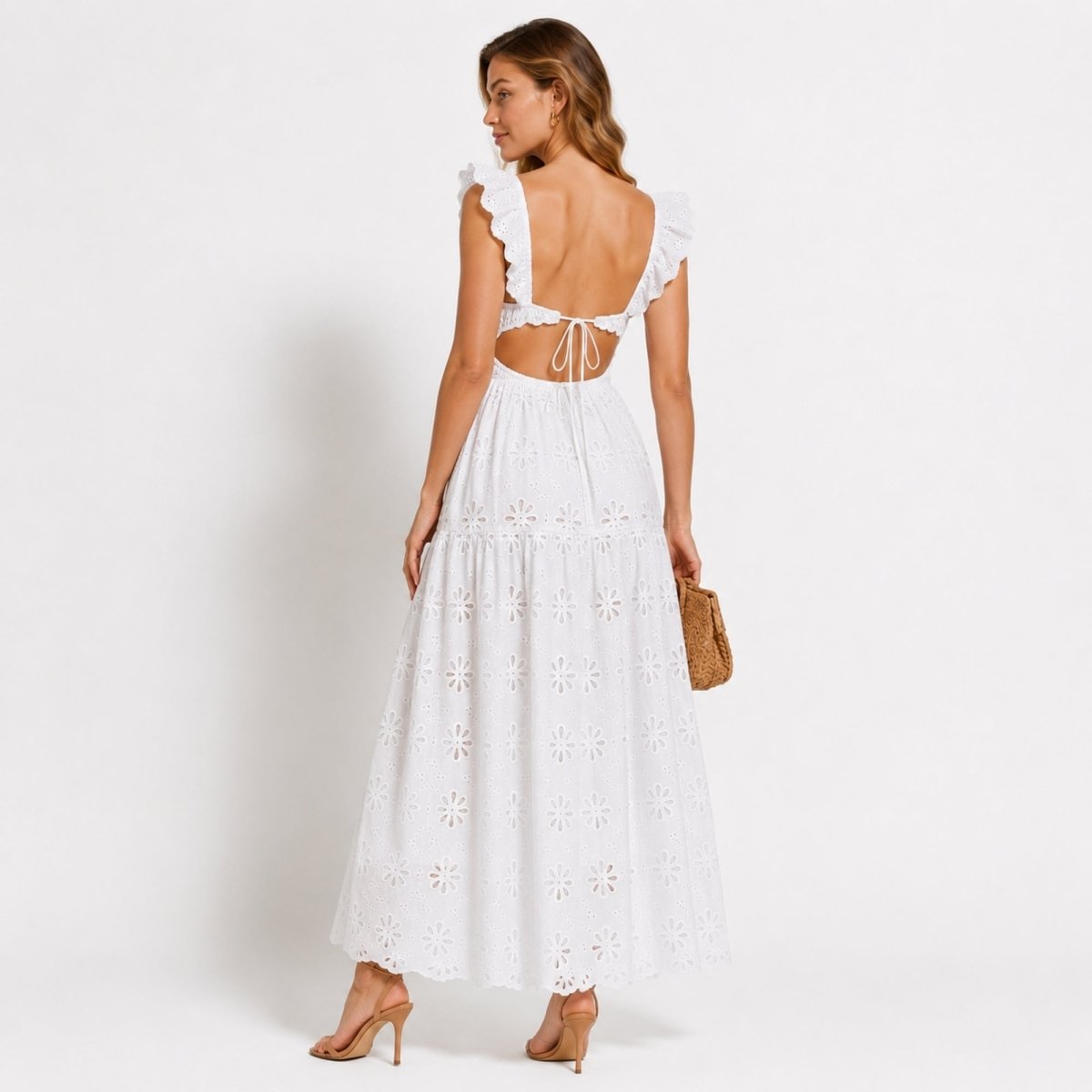Back view of Kouvr white luxury resort wear dress featuring a cutout open tie-back design and sweeping tiered eyelet lace skirt.