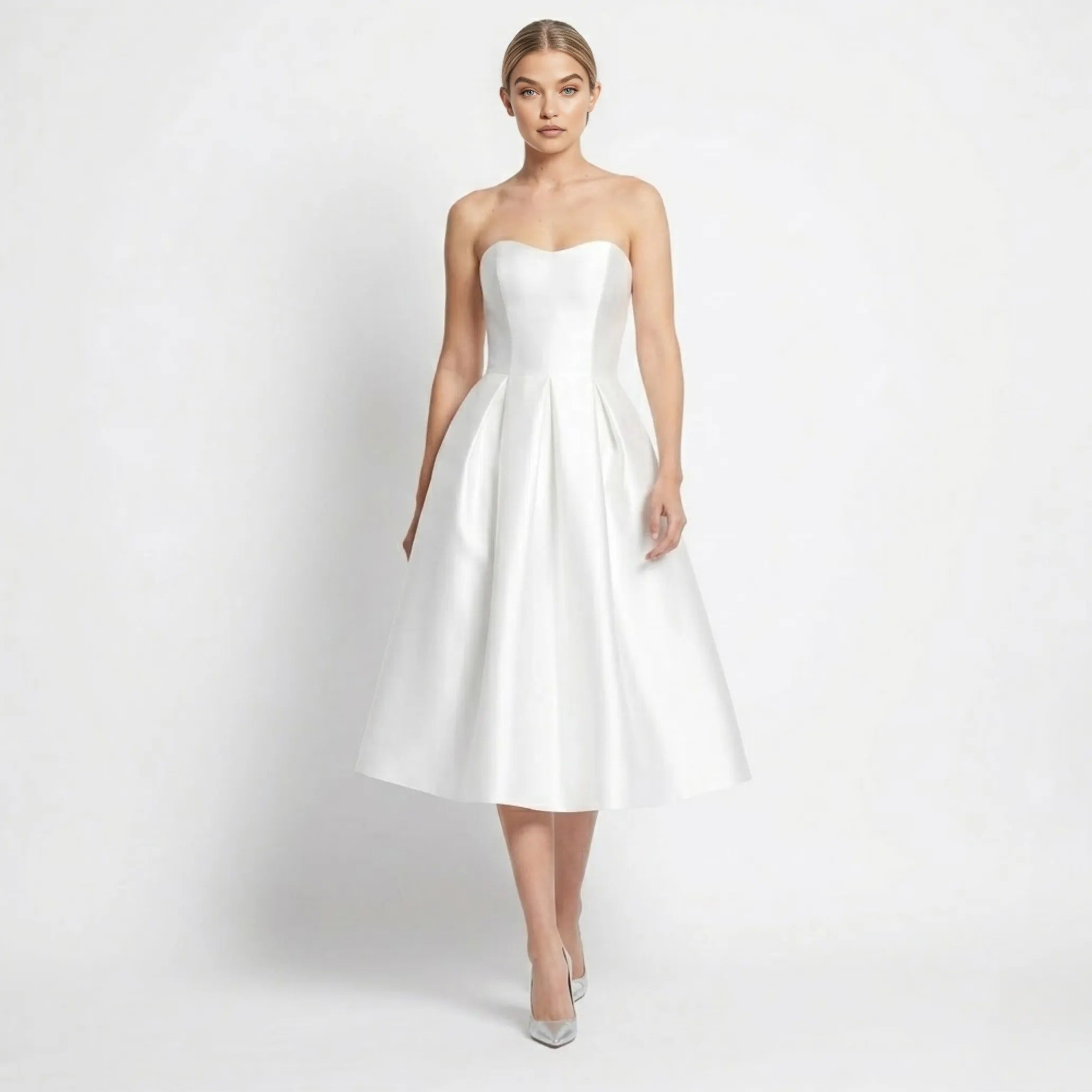 Woman walking wearing a white strapless satin midi dress with pleated A-line skirt by Kouvr.