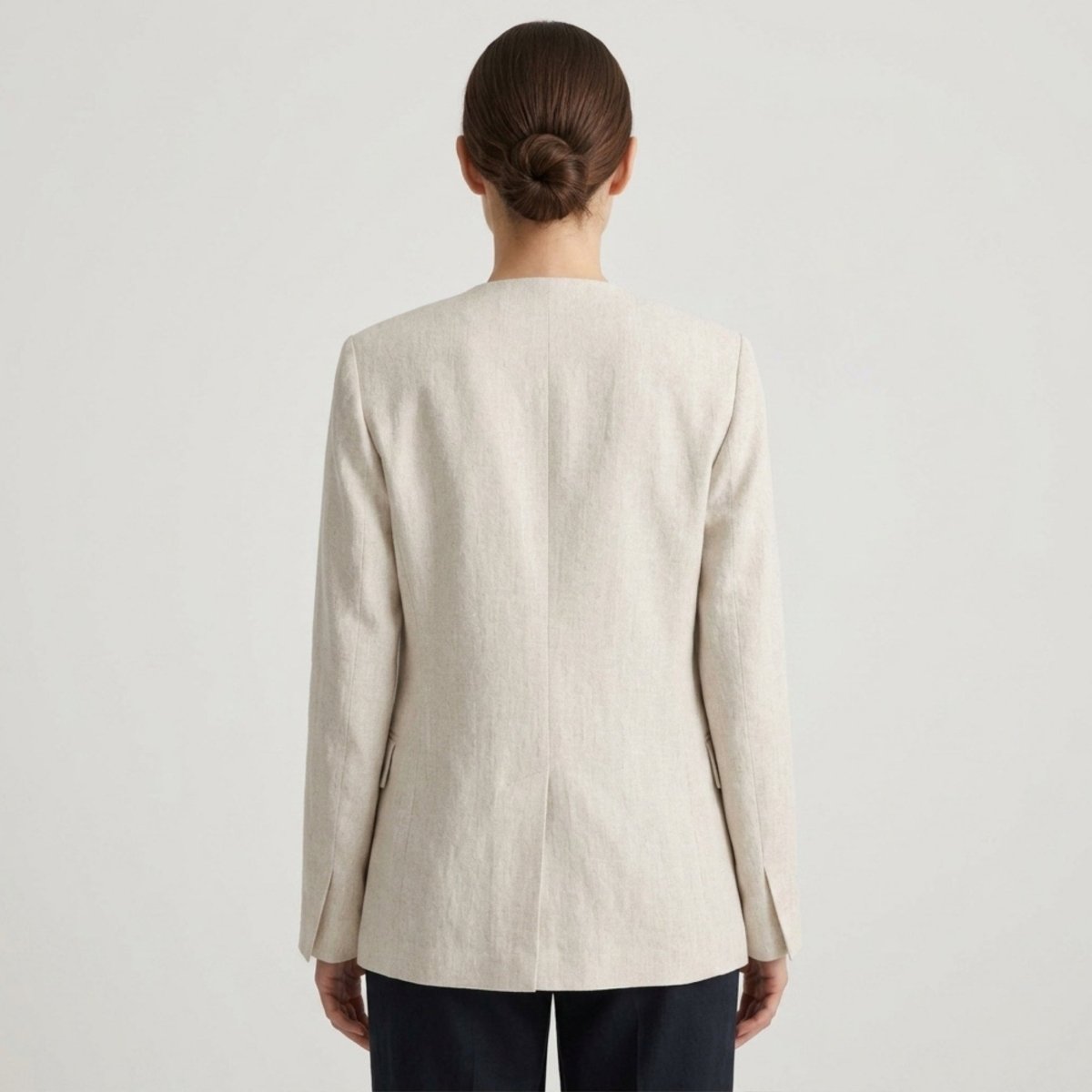 Back view of a tailored light beige single button women's blazer with a center back vent.