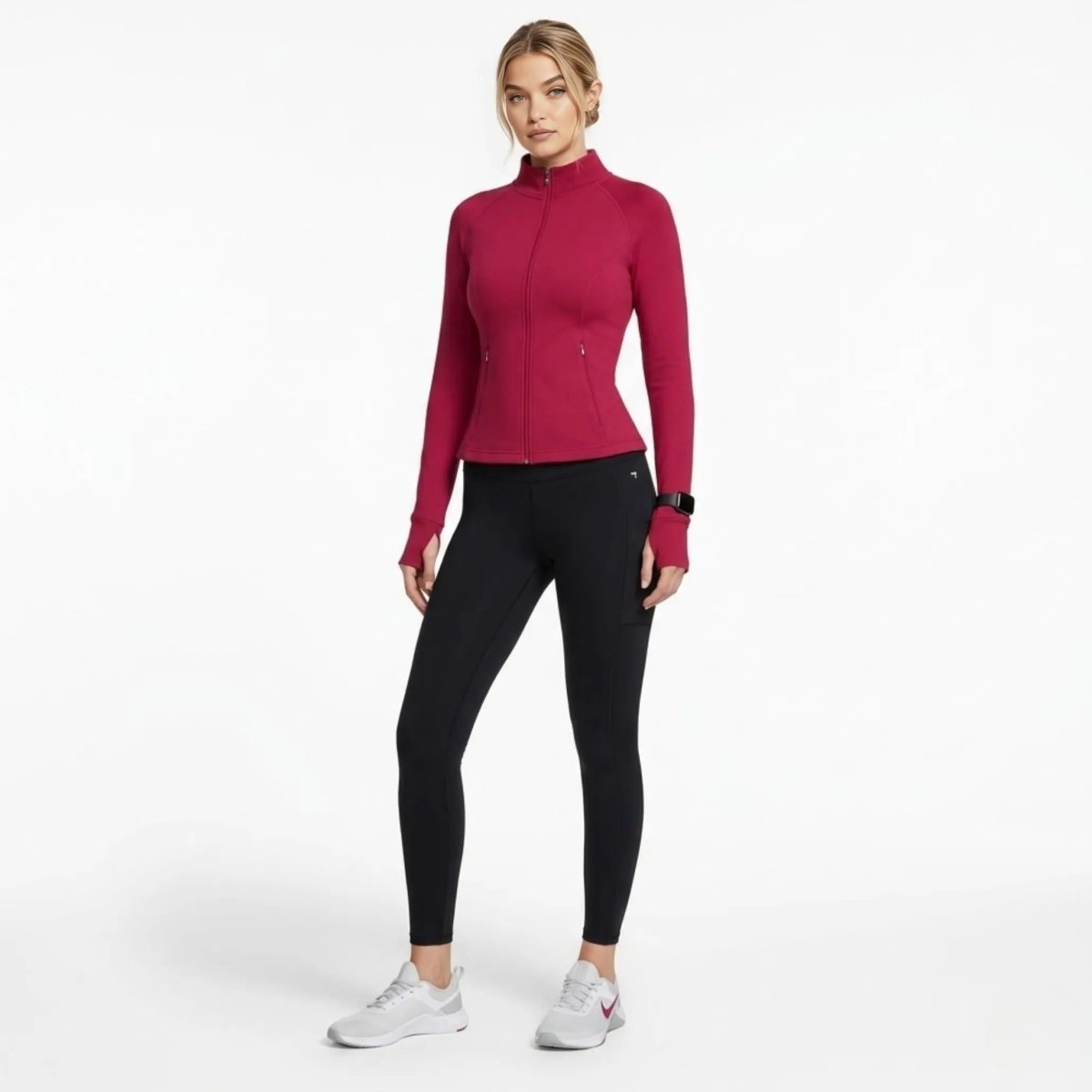 Woman walking wearing fitted berry red workout zip up jacket and black leggings