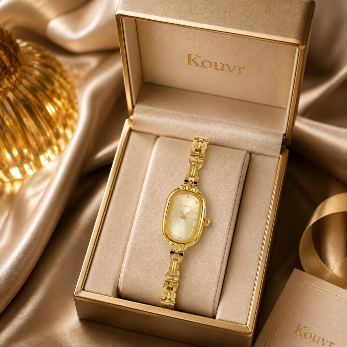 Kouvr women's gold oval watch displayed inside a luxury beige presentation gift box resting on elegant golden silk fabric.