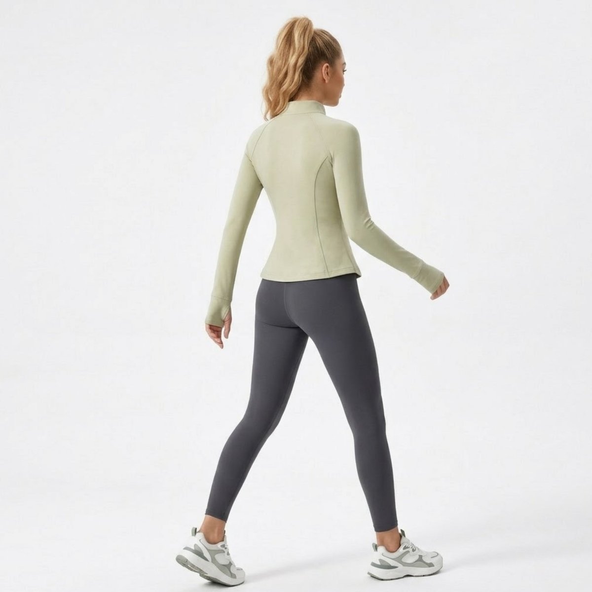 Back angle of woman demonstrating the flexible, second-skin fit of the green activewear jacket.