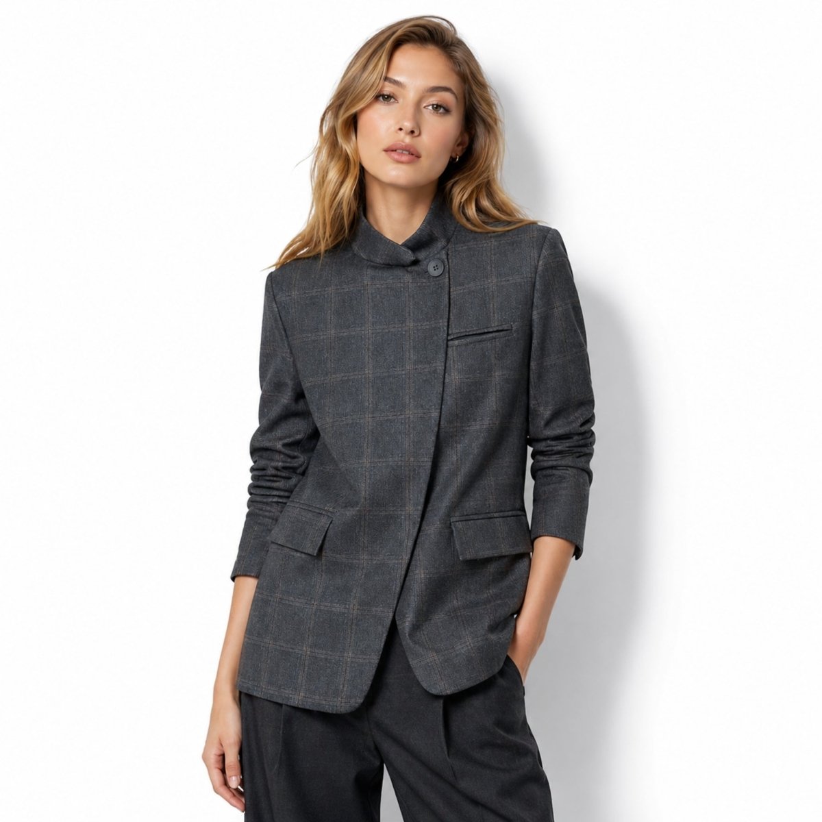Three quarter view of the Kouvr grey plaid blazer highlighting the flap pockets and high collar design.