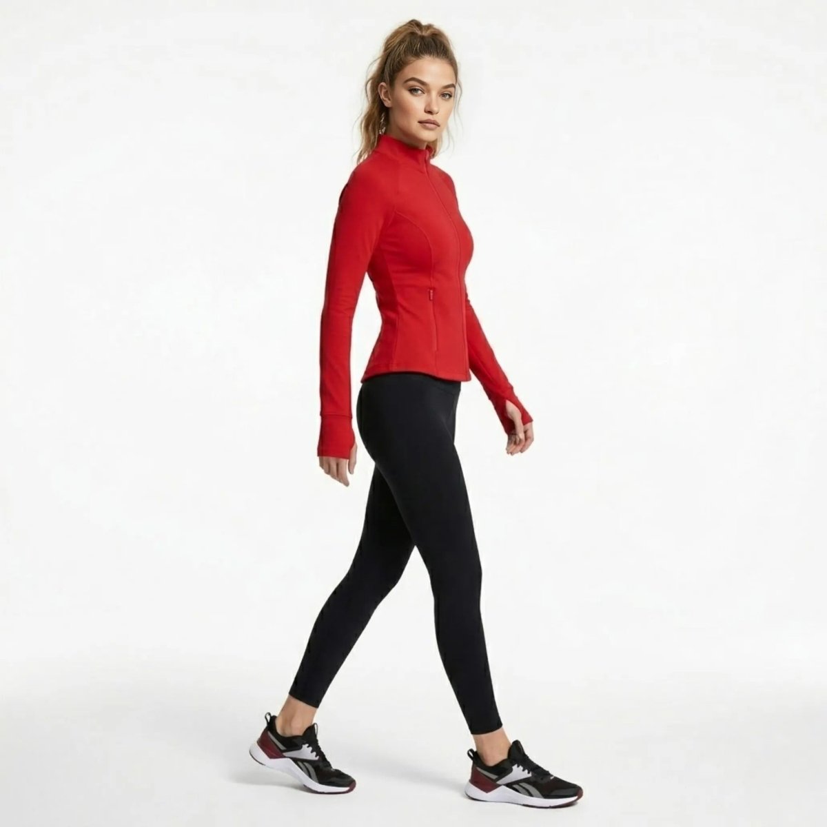 Side profile of woman walking in red fitted athletic track jacket and black workout pants