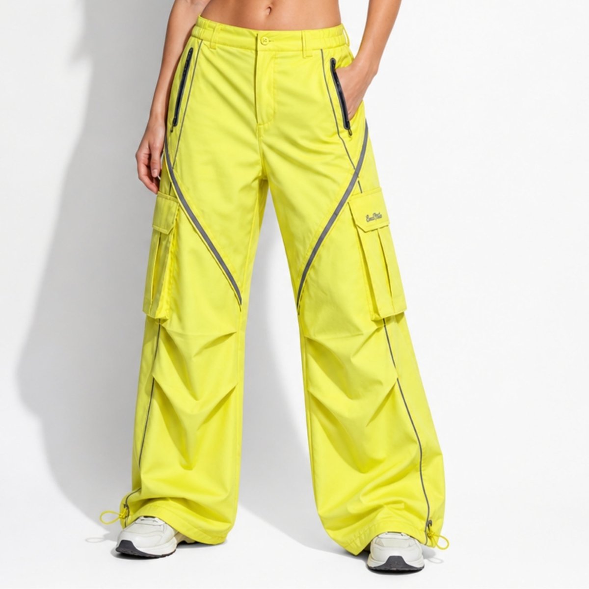 Front view of women's neon yellow wide leg parachute cargo pants with reflective piping and multiple pockets