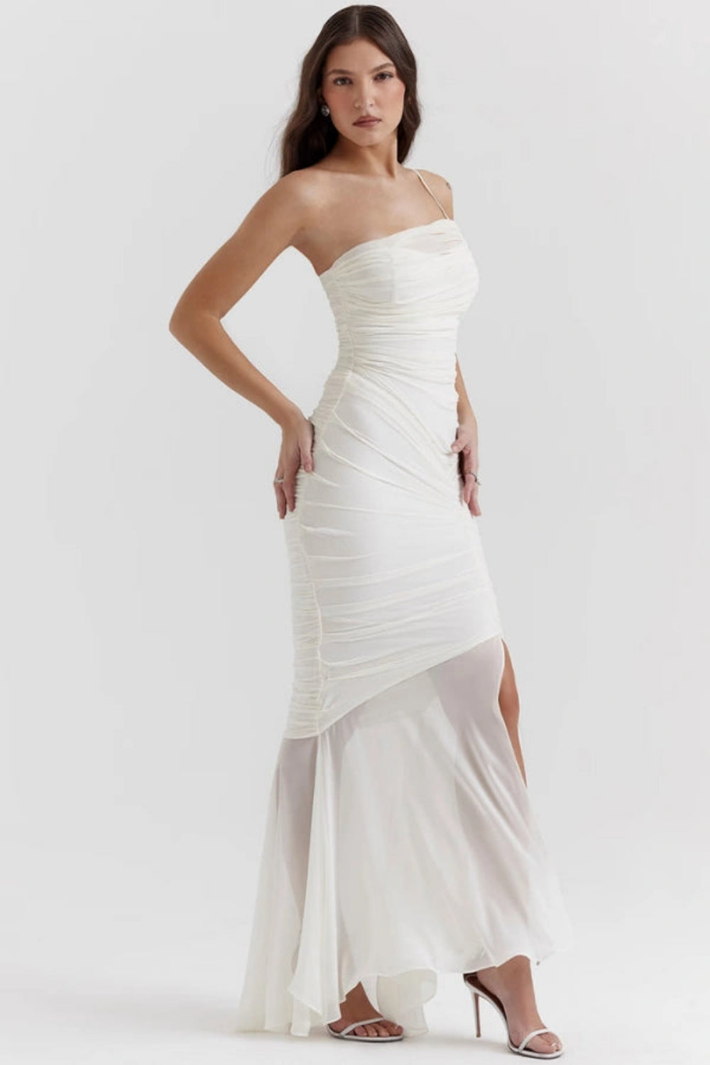 Model wearing the Kouvr Fashion Ruched white one-shoulder ruched maxi dress with a sheer mermaid hem and thigh-high slit