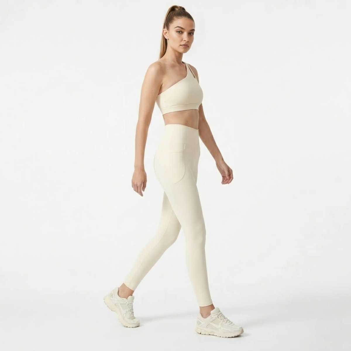 Side angle of woman walking in Kouvr matching arpicot athletic set highlighting deep side pockets on high waisted sculpting leggings.
